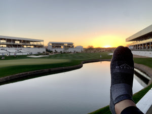 Sock overlooking hole 17 at the Phoenix Open with a pond in the foreground and a sunset in the background.